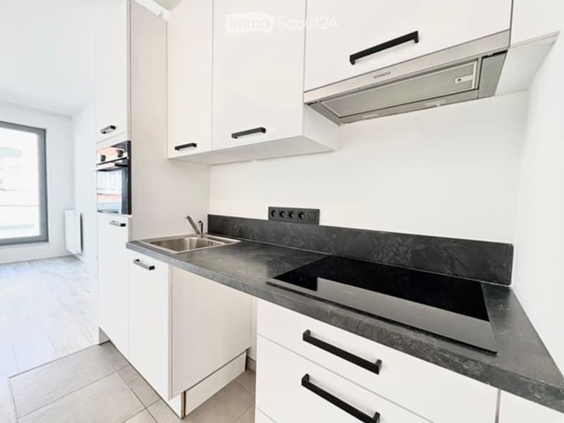 Modern kitchen with white cabinets, black granite countertop, stainless steel sink, induction cooktop, and range hood.