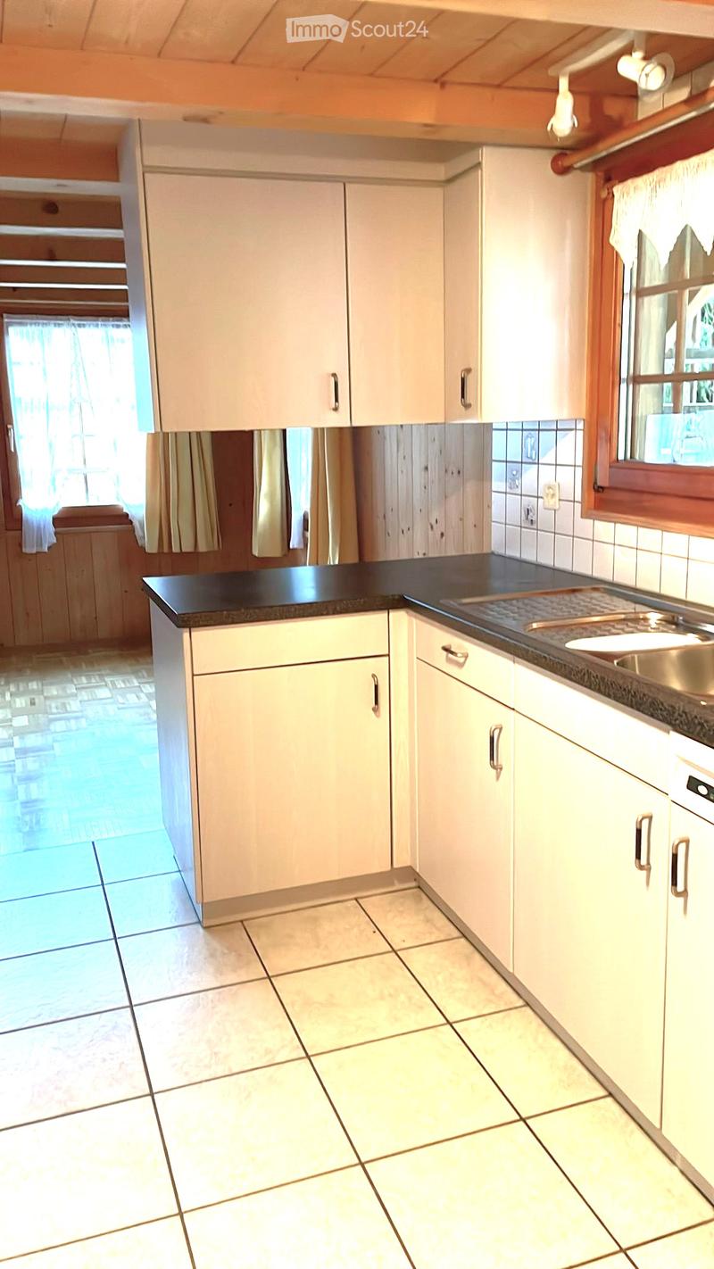 Bright kitchen with white cabinets, black countertop, and tiled floor. Features a sink and a window with curtains.