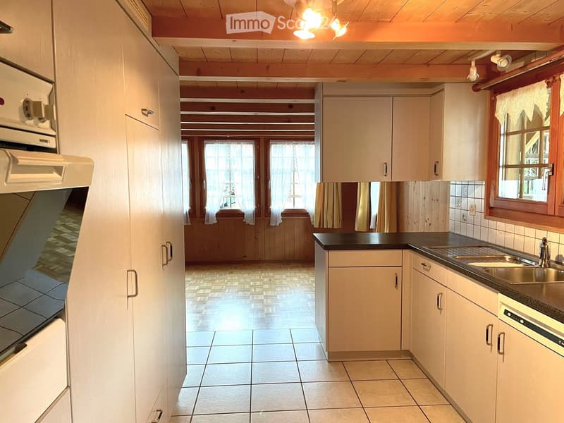 Bright kitchen with white cabinets, black countertop, stainless steel sink, and built-in appliances.