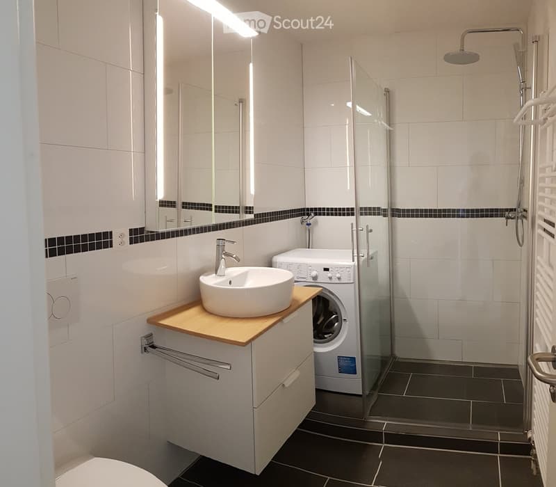 modern white bathroom, large mirror, white sink, wooden countertop, modern white shower, washing machine