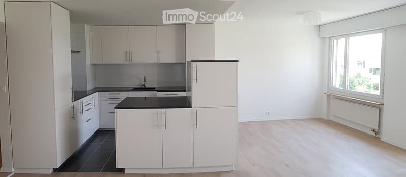 modern kitchen, white cabinets, black countertops, white tiled backsplash, stainless steel faucet, white walls, wooden floor, large window
