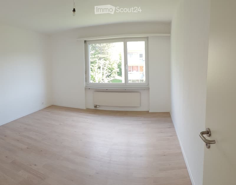 wooden floor, white walls, corner window, white radiator, power outlet