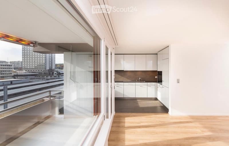 Modern, minimalist kitchen with white cabinets, a sink, and a large window offering a city view.