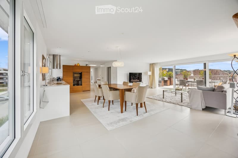 Open-plan living and dining area with modern furniture, large windows, and a view of the outdoor space.