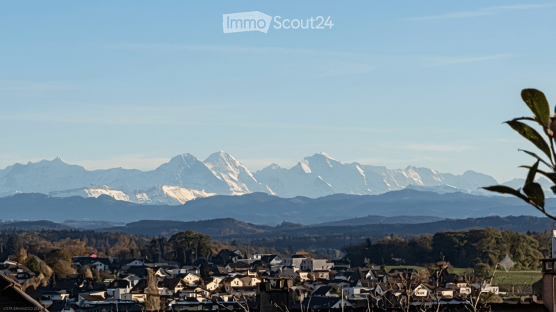 Panoramic view of a town nestled in a valley with snow-capped mountains in the background.