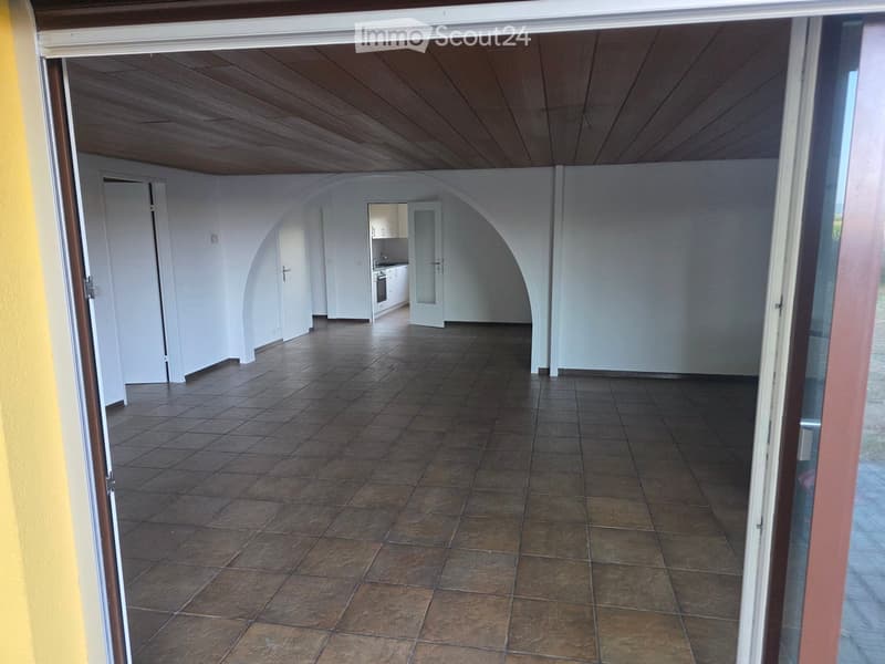 Empty room with tiled floor, white walls, and wooden ceiling. No furniture or equipment present.