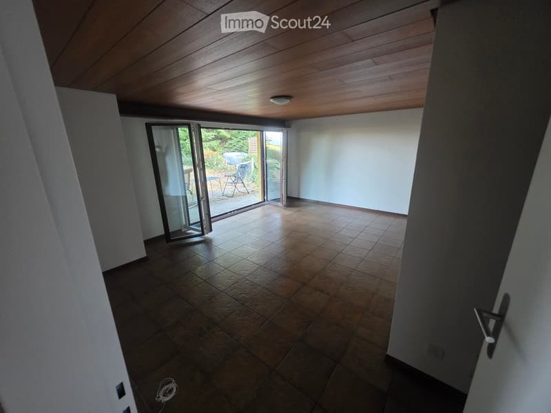 Empty room with tiled floor, white walls, and a large sliding glass door leading to an outdoor area.