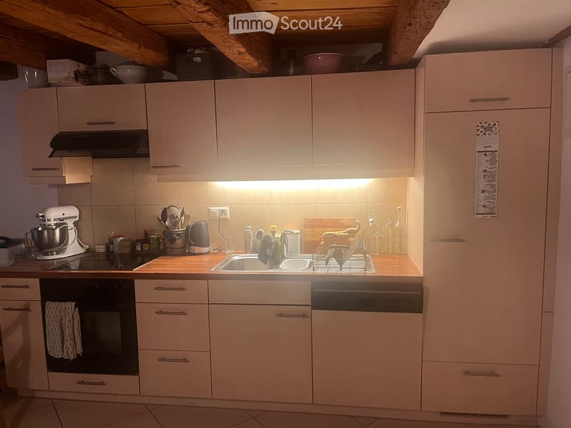 Modern kitchen with light-colored cabinets, stainless steel appliances, and a wooden countertop. Features include an oven, sink, dishwasher, mixer, and various kitchen utensils.