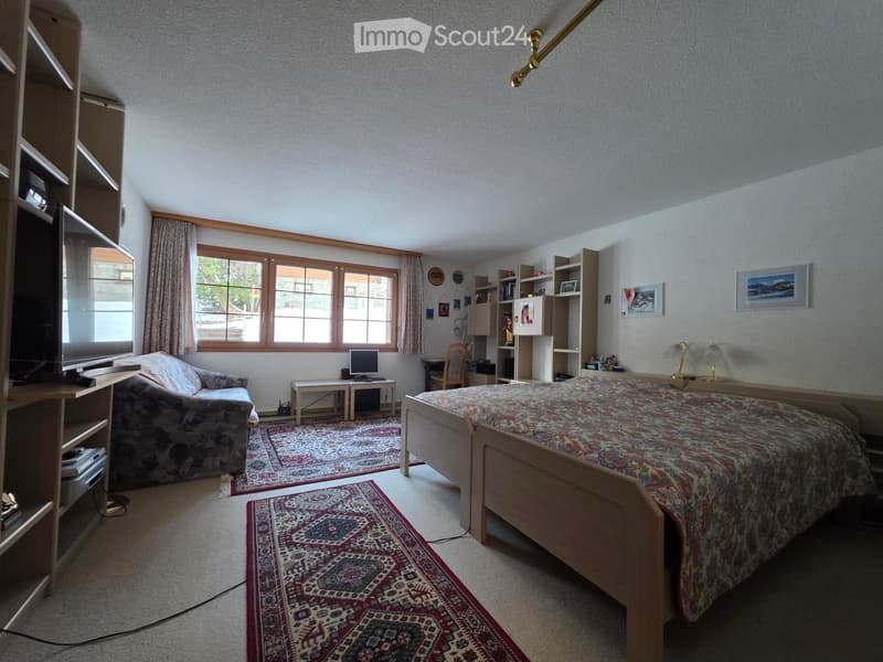 Bedroom with two beds, couch, desk, TV, carpet, shelves, picture frames, window with curtains