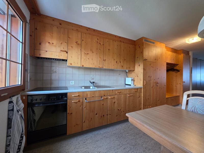 kitchen with wooden cabinets, black oven, sink, tiled backsplash, wooden table, window