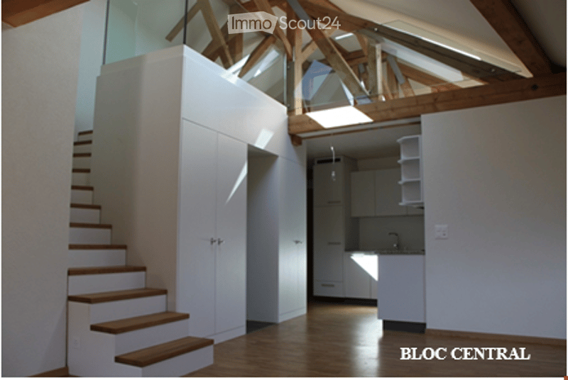 Modern interior with a staircase leading up, white kitchen cabinets, and a sink in the corner.