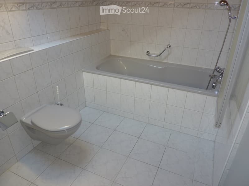 Bathroom with a toilet, bathtub, and a showerhead, featuring tiled walls and floor.