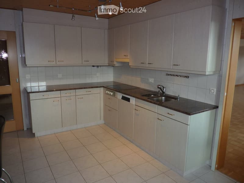 modern, functional kitchen with white cabinetry, black countertops, stainless steel sink and dishwasher, tiled flooring