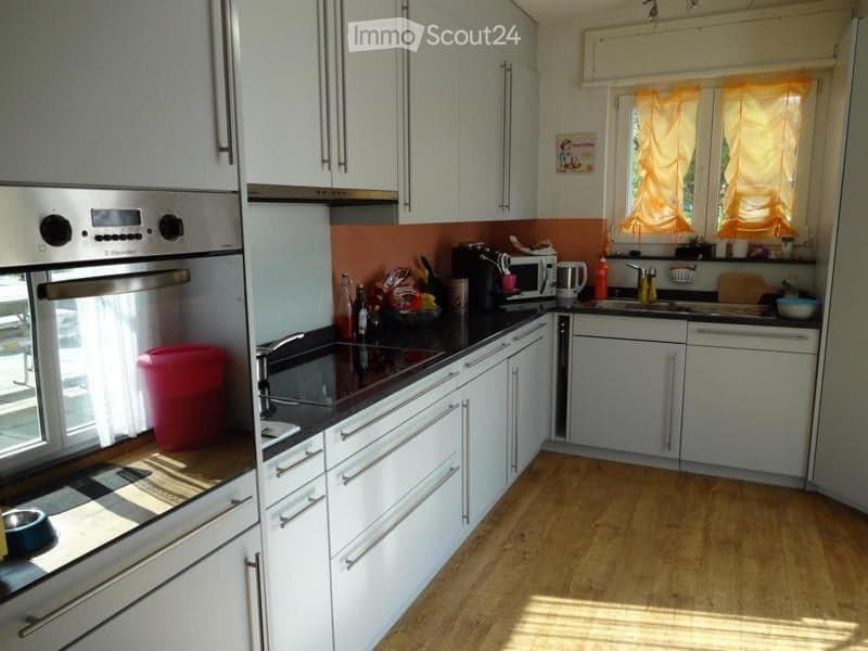 Modern kitchen with white cabinets, black countertops, and stainless steel appliances. Features include an oven, microwave, sink, and various kitchen items on the counter.