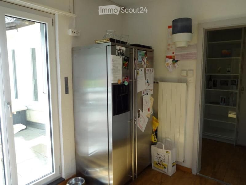 Modern kitchen with stainless steel refrigerator, radiator, shopping bag, and pet bowl on the floor.