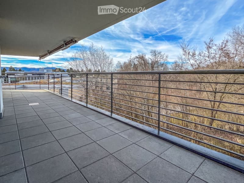 Balcony with tiled floor, metal railing, and scenic view of trees and mountains.