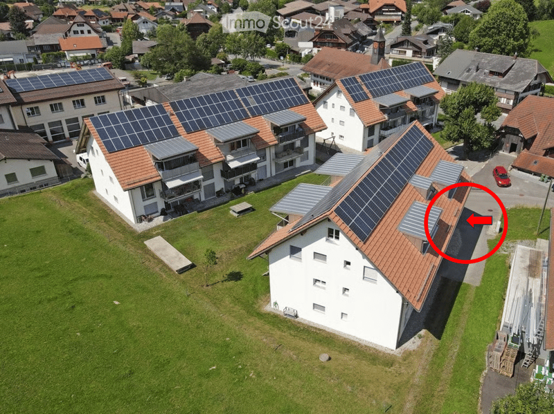 Aerial view of a residential area with multiple houses, solar panels on roofs, and a well-maintained lawn.