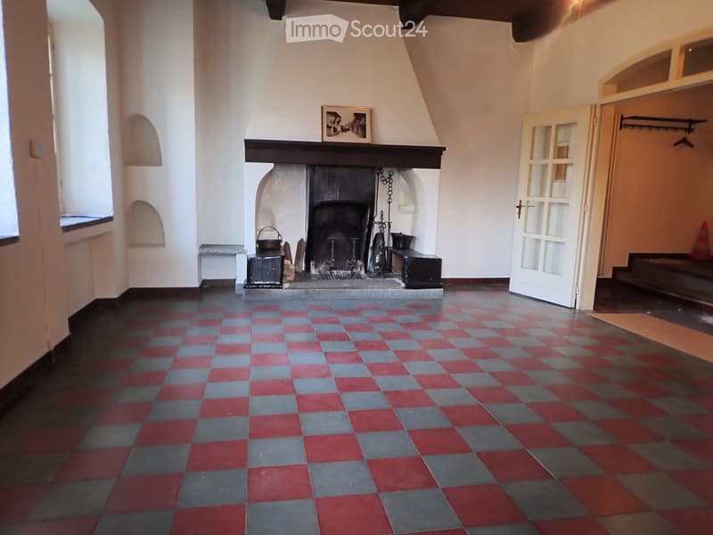 Empty room with a fireplace, checkered floor, and large windows. No furniture or equipment present.