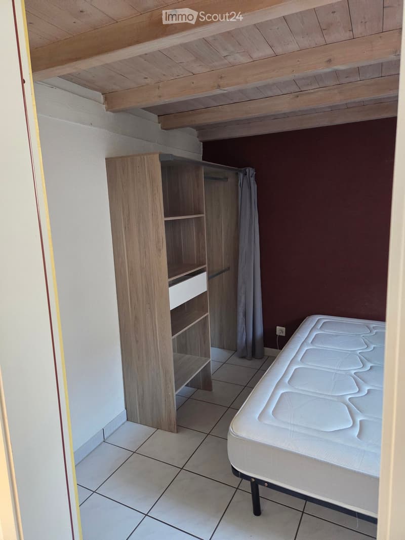 Bedroom with a tiled floor, wooden wardrobe, and a mattress on a bed frame.