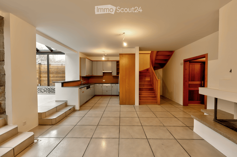 Open kitchen, fireplace, tiled floor, wooden staircase, large windows
