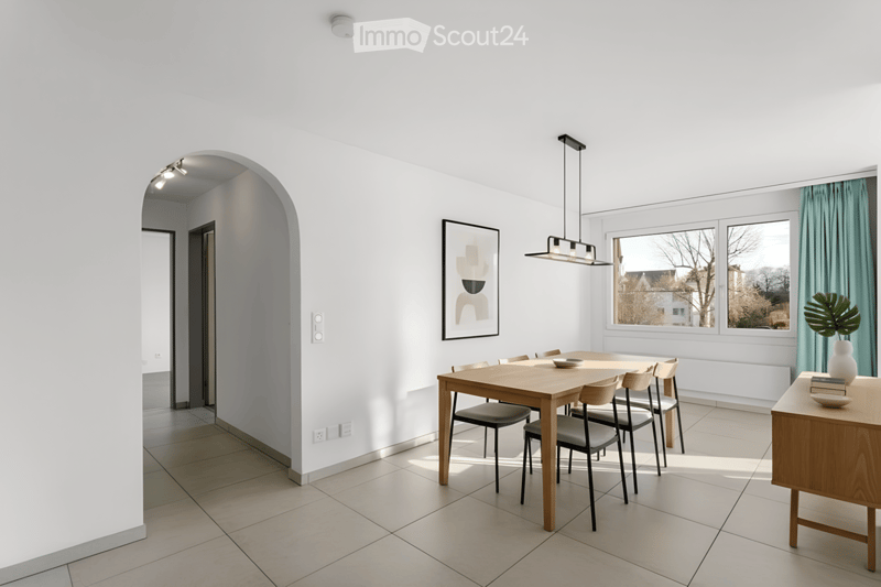 Bright dining area with a wooden dining table and chairs, a side table with a vase and books, and a modern pendant light fixture.