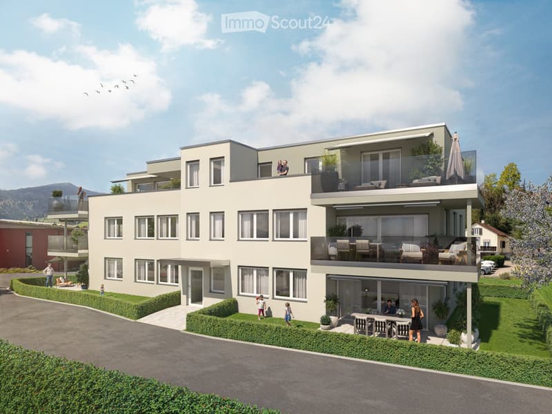 Modern two-story residential building with balconies, large windows, and landscaped surroundings. Features include outdoor seating areas, potted plants, and a well-maintained lawn.