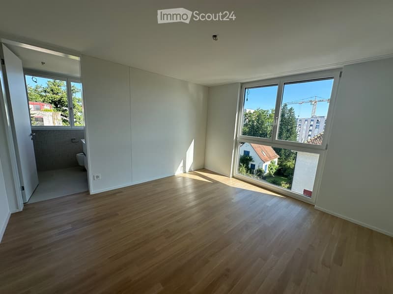 Empty room with wooden flooring, large windows, and a view of the outside. The room is unfurnished with no visible furniture or equipment.