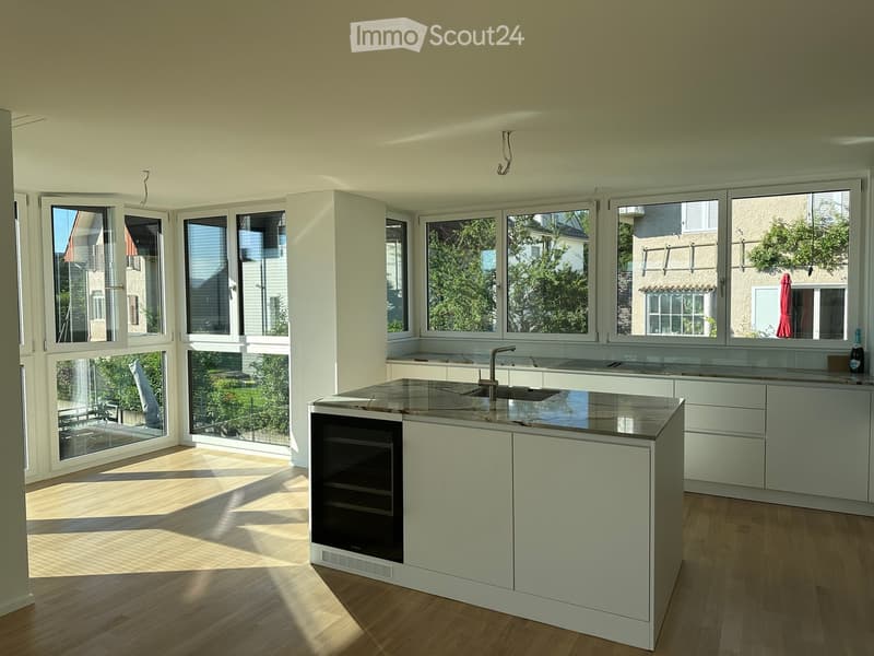 Modern kitchen with white cabinets, a central island with a marble countertop, and large windows letting in natural light.