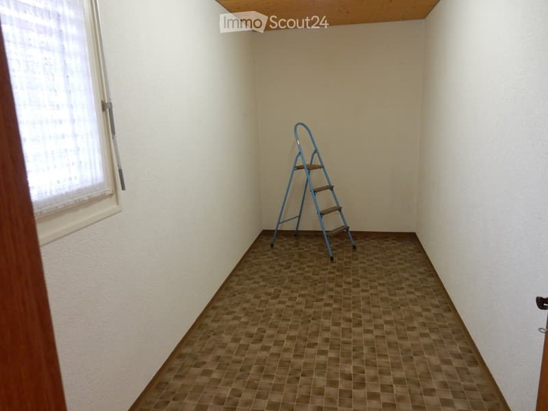 Empty room with white walls, wooden ceiling, and a tiled floor. A metal ladder is placed in the corner of the room.