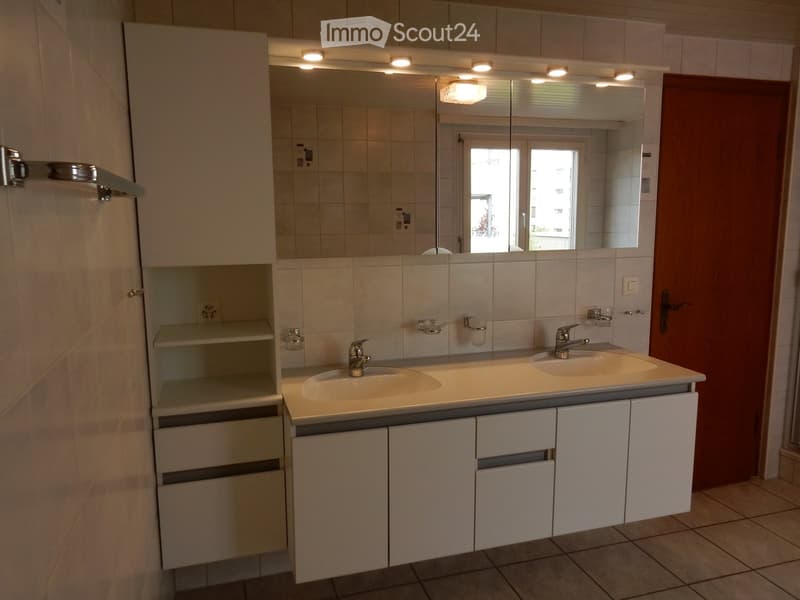 Tiled walls, double sink vanity, storage cabinet, recessed lighting, window