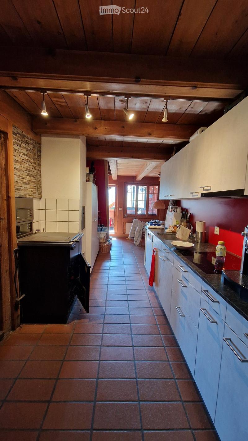 Modern kitchen with white cabinets, stainless steel appliances, tiled floor, and a window at the end of the room.