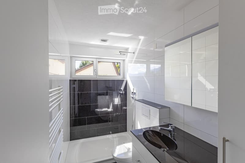 Modern bathroom with white tiles, a black sink, a bathtub, a toilet, a shower area, a large mirror, and a radiator.