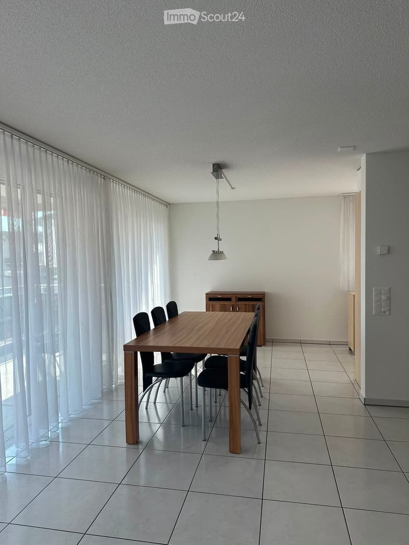 Dining room with a wooden dining table, six black chairs, a small wooden cabinet, and a hanging light fixture.
