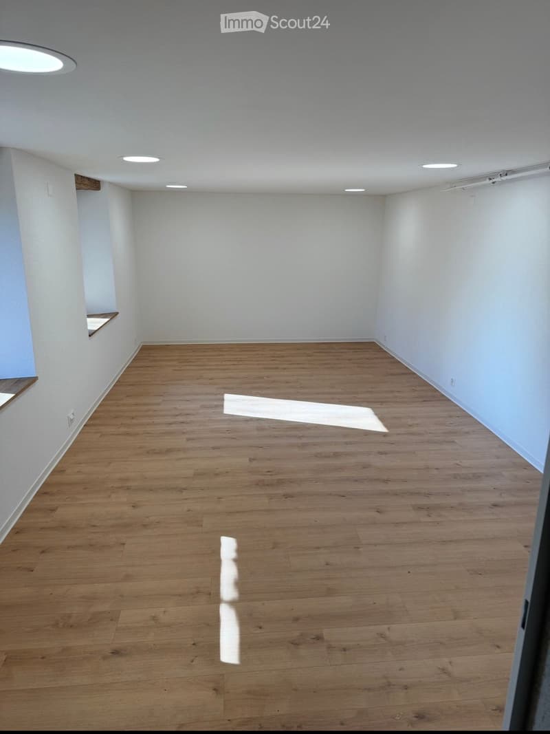 Empty room with wooden flooring and white walls, featuring recessed ceiling lights and a small built-in shelf on one wall.