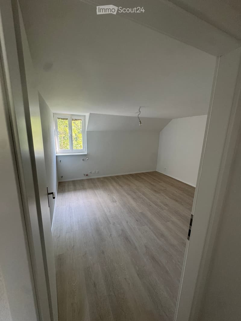 Empty room with wooden flooring, white walls, and a window letting in natural light. No furniture or equipment is present.