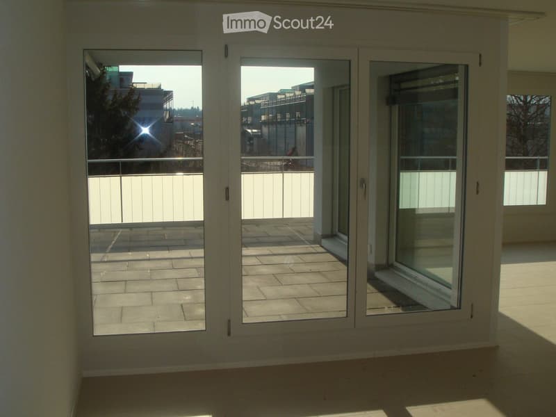 Empty room with large sliding glass doors leading to a tiled balcony area, featuring a metal railing and a view of the outside.