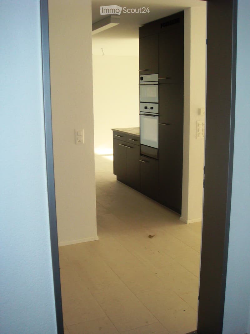 An empty room with light-colored walls and a tiled floor, featuring built-in cabinets and a small window at the top.