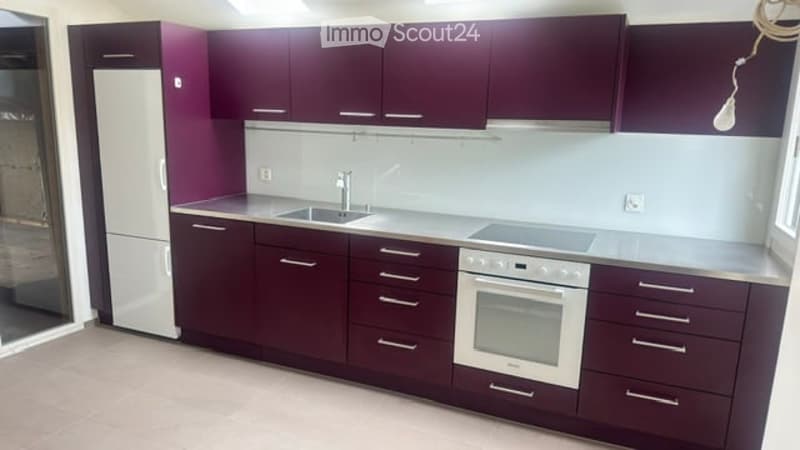Modern kitchen with dark purple cabinets, white appliances, and a clean, minimalist design.