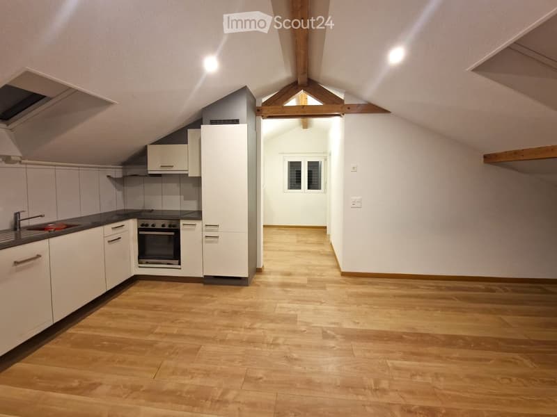 empty attic kitchen with white cabinets, wooden floors, wooden beams, kitchen appliances, white ceilings
