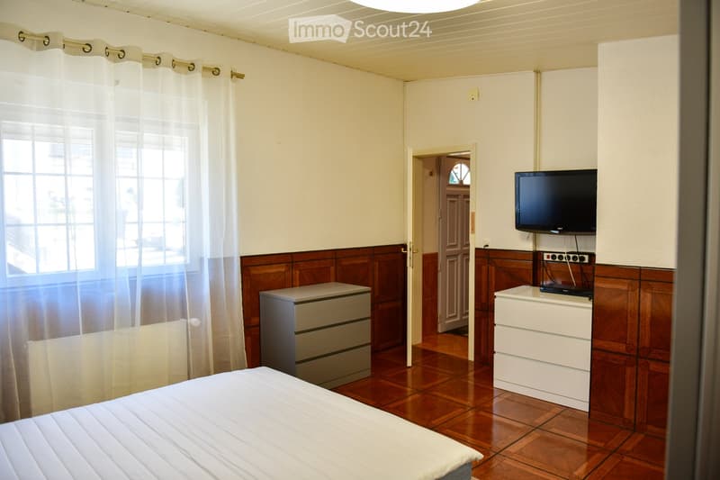 single bed, large window, radiator, TV, dresser, wooden flooring
