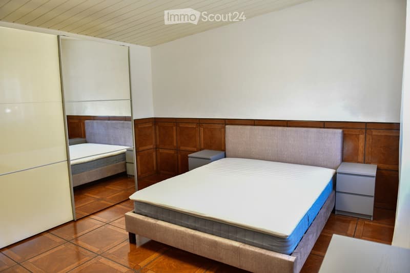 wooden floor, double bed, white walls, wooden headboard, two nightstands, mirror