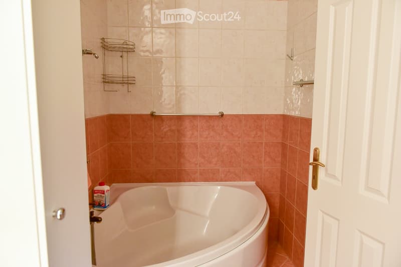 white bathtub, tiled walls, cleaning product on the side