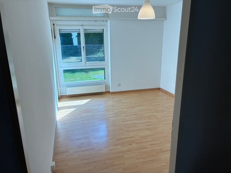 Empty room with light wooden flooring, white walls, and large windows allowing natural light. No furniture or equipment is present.