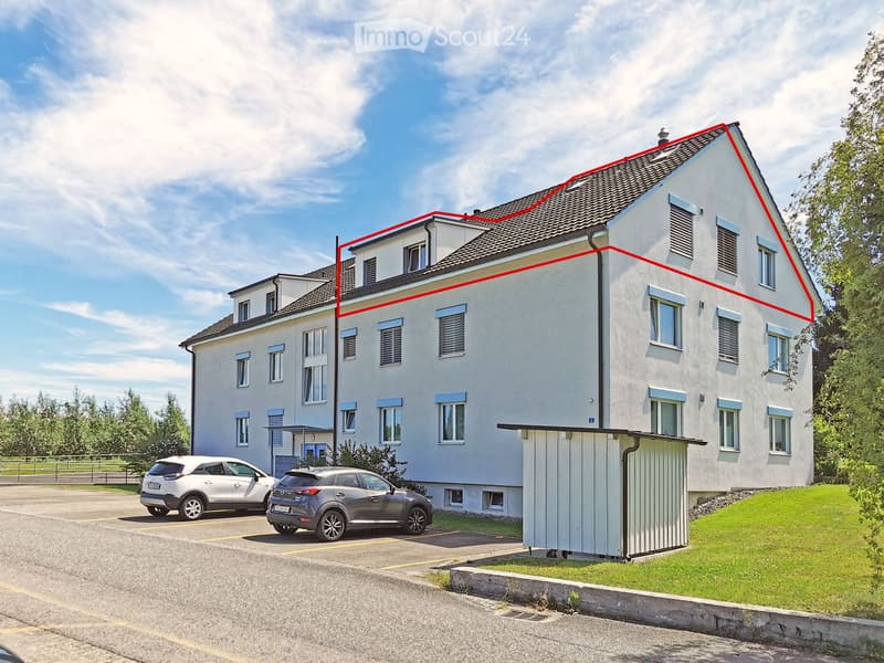 Two-story white house with multiple windows, a garage, and a parking area with two cars.