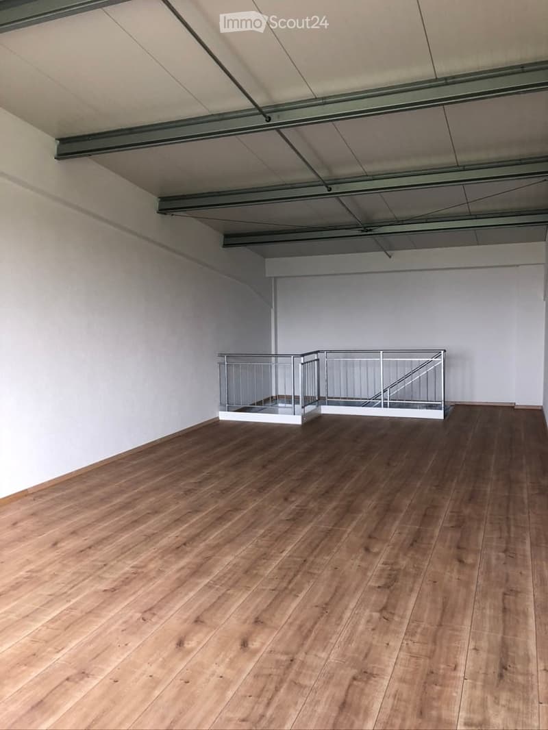 Empty room with wooden flooring, white walls, and a small metal staircase leading to an upper level.