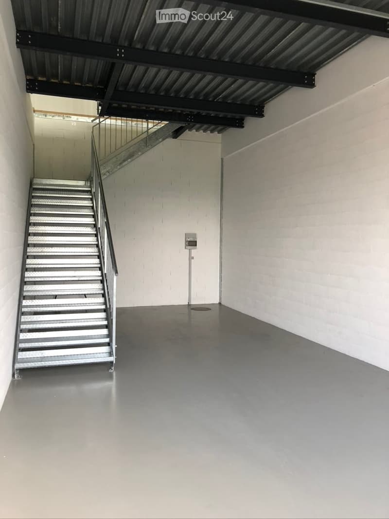 Empty room with a metal staircase leading to an upper level, white brick walls, and a polished concrete floor.