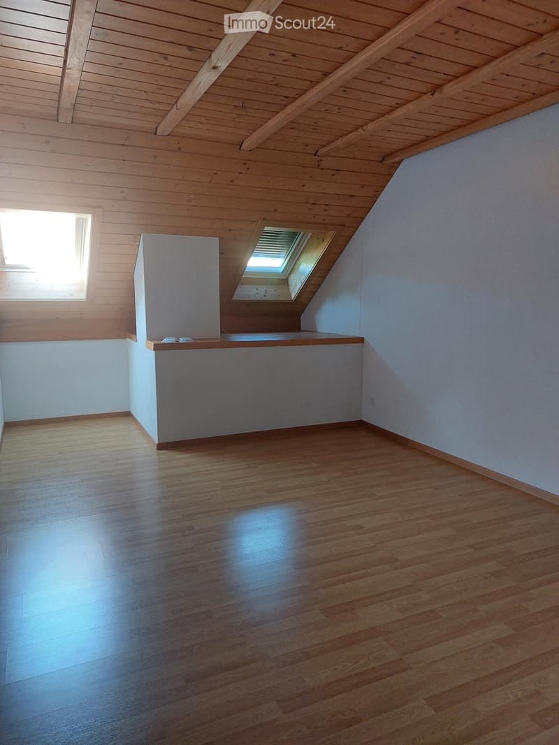Empty attic room with wooden ceiling, wooden floor, and skylight window. No furniture or equipment present.