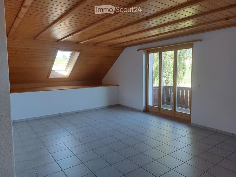Empty room with wooden ceiling, tiled floor, large window, and sliding glass doors leading to a balcony.