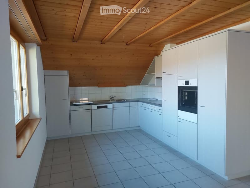 Modern kitchen with white cabinets, tiled floor, and stainless steel appliances including a refrigerator, dishwasher, and oven. The ceiling has exposed wooden beams.