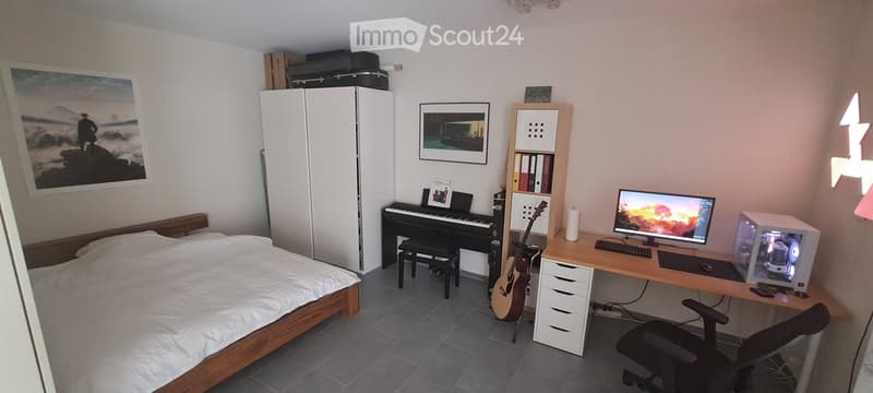 A furnished room with a bed, desk, chair, guitar, piano, and various storage items.